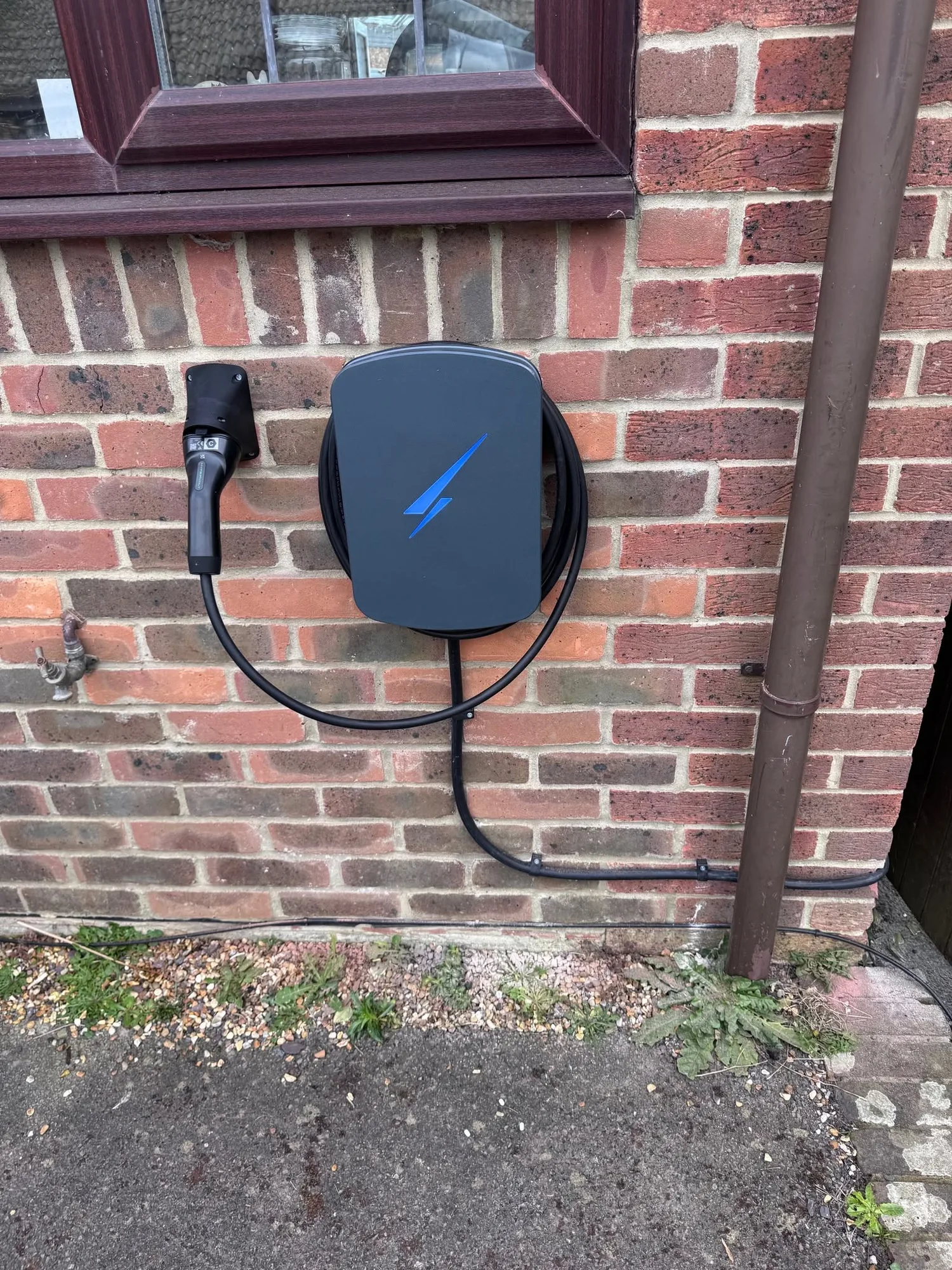 Tethered EV charger neatly installed on a red brick house wall
